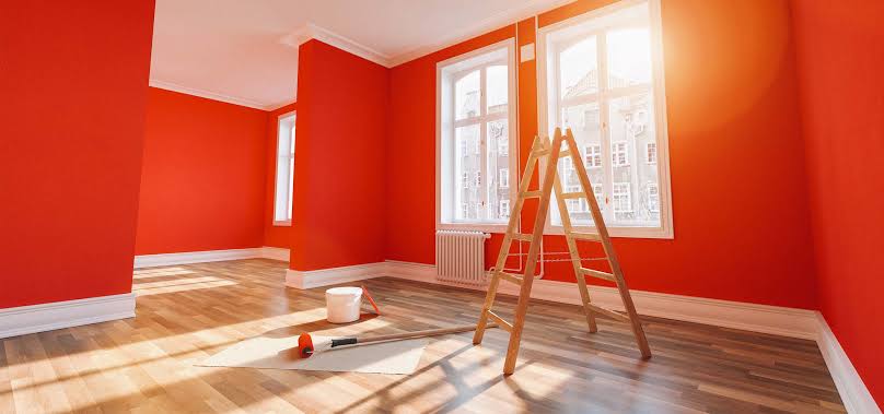 Bold red-orange room being painted with tall ladder